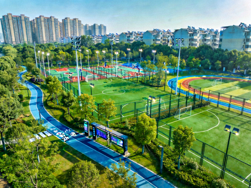 社区智慧体育公园全景俯瞰图 - 绿树环绕，智能步道与球场错落有致