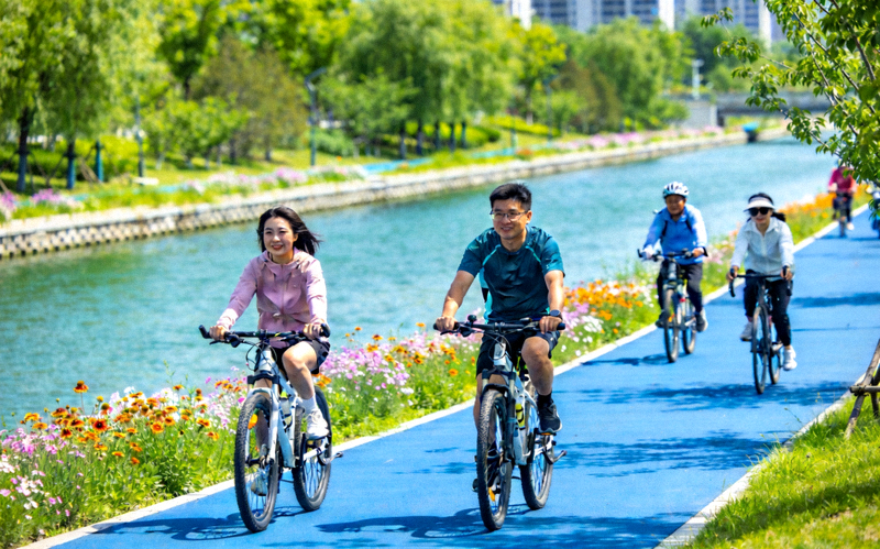 城市绿道骑行健身 - 市民在沿河绿道上骑行，享受户外运动