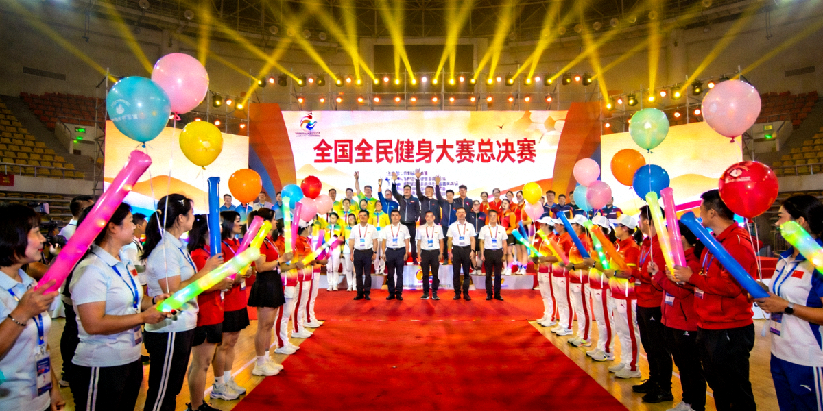 全国全民健身大赛总决赛闭幕式现场，参赛选手与观众齐聚体育馆，气氛热烈